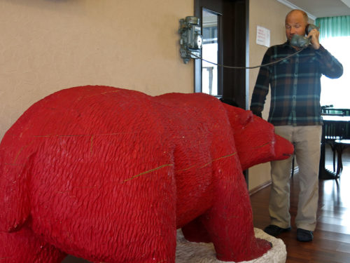 Willie chatting on the phone while a huge red bear sniffs his, uhmm, pants.
